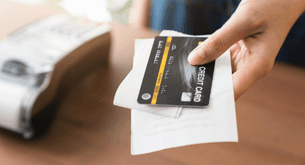 A cashier holds out a credit card and receipt.