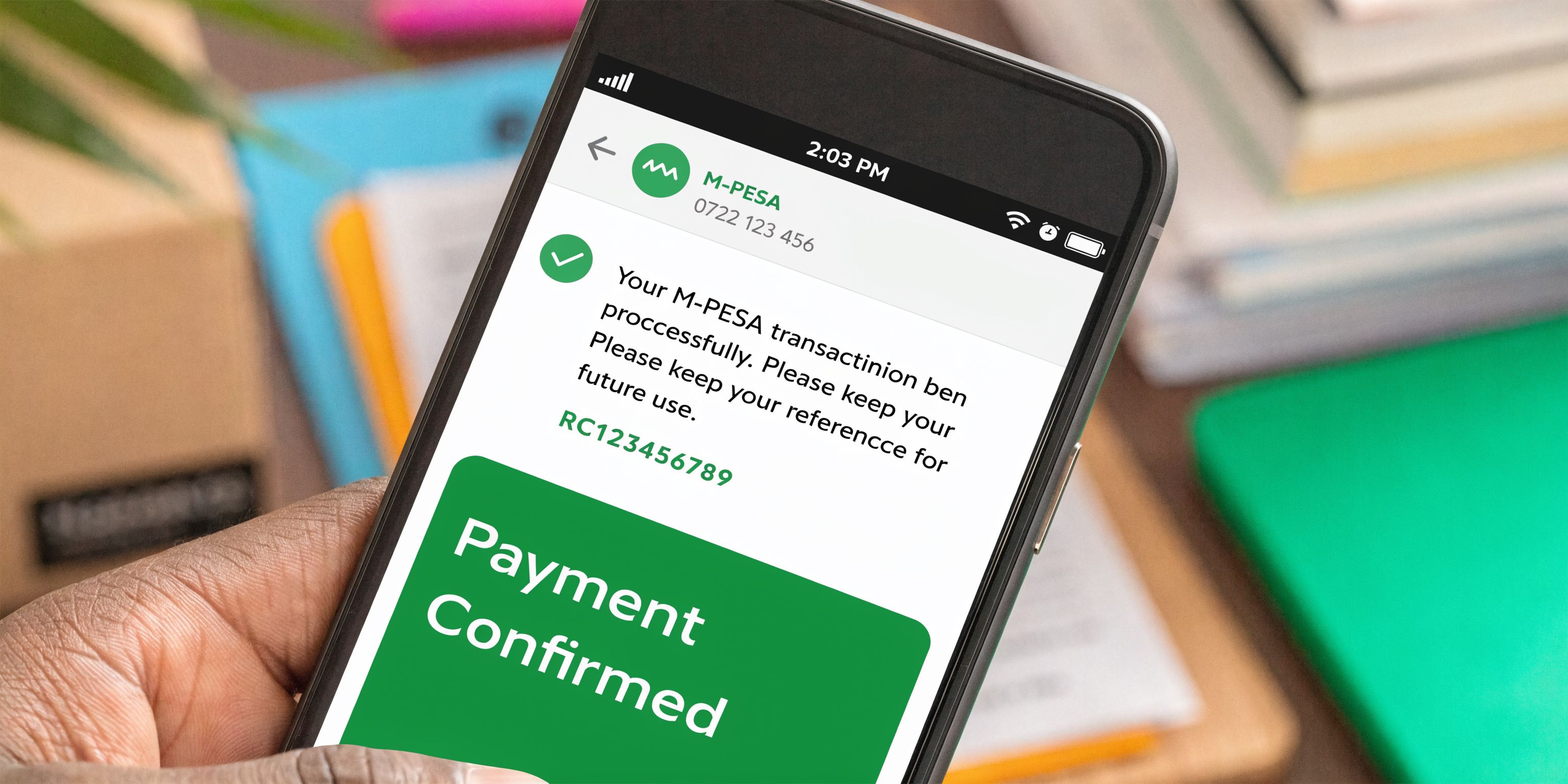 A smartphone held in a hand showing an M-PESA payment confirmation message on its screen.