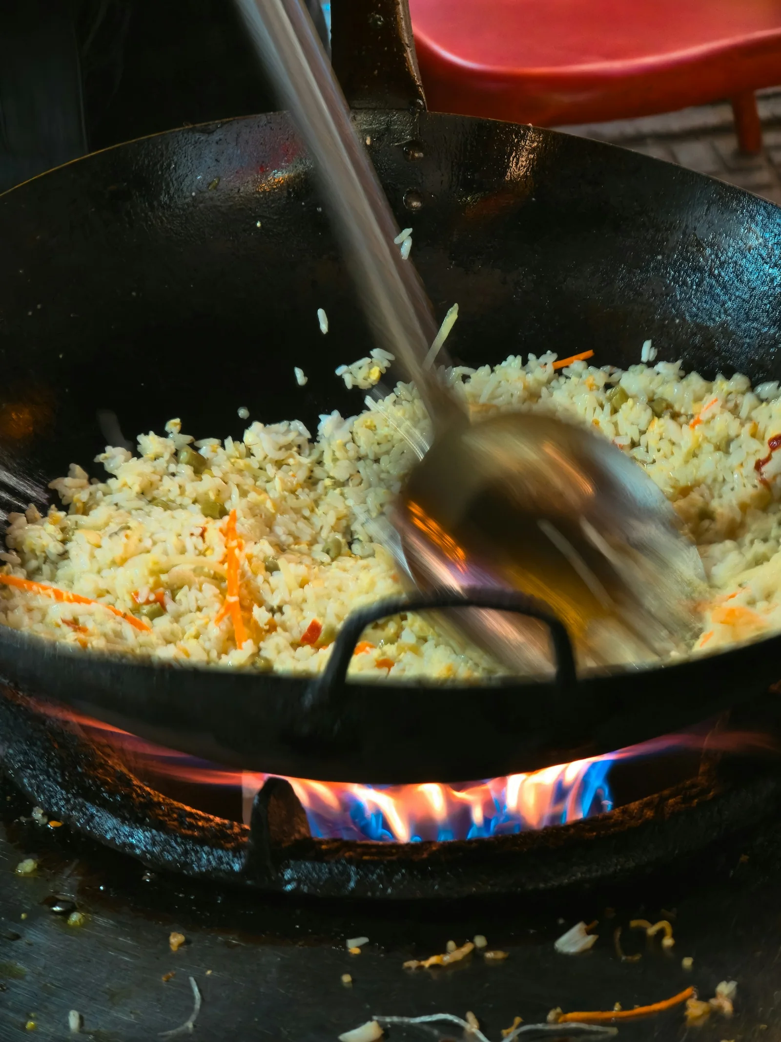 Fried rice tossed over a blue flame in a black wok