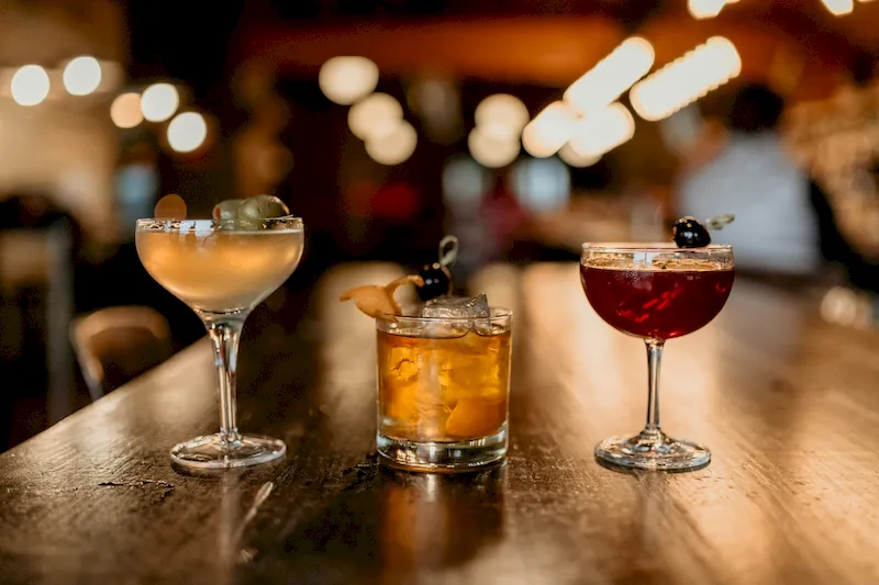Three cocktails sitting on a bar