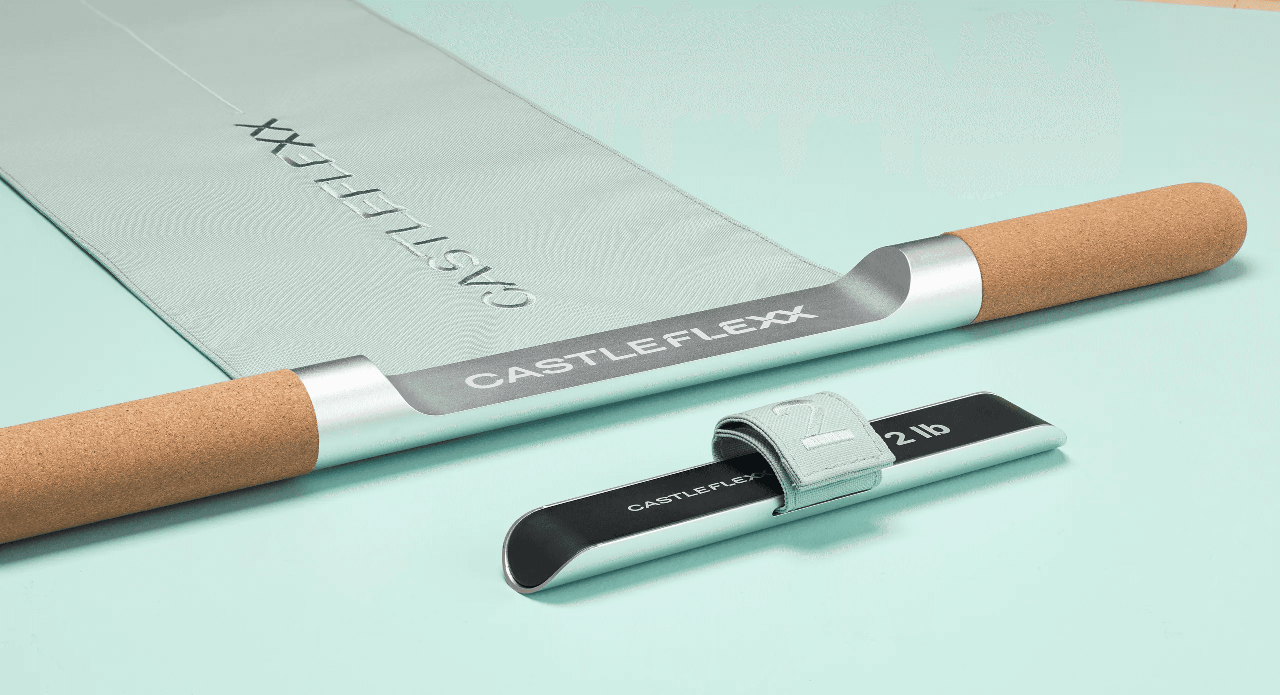 CastleFlexx device displayed with its fabric strap and compact accessory on a light blue background