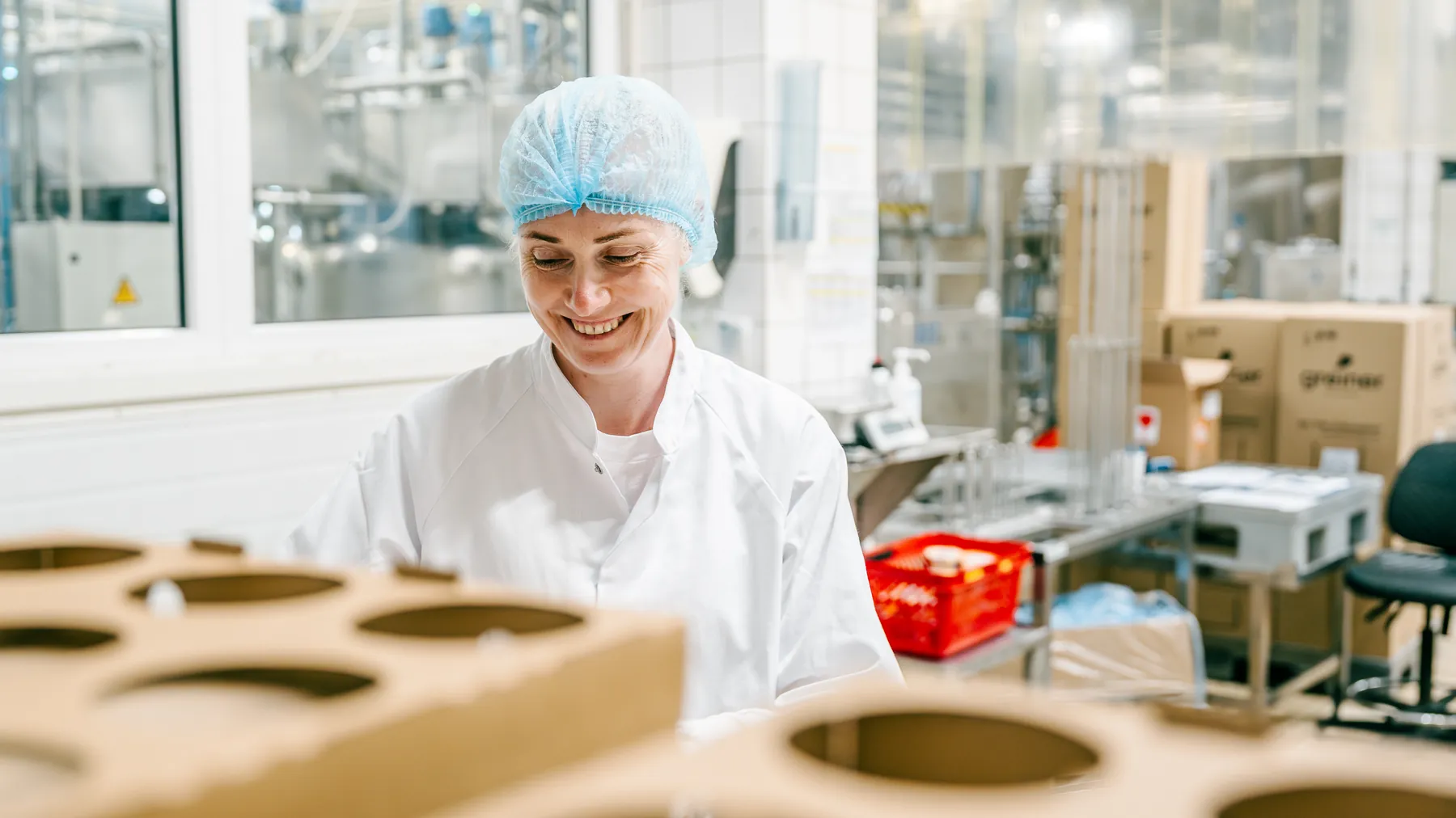 Smiling factory worker in a hairnet packing product into cardboard trays