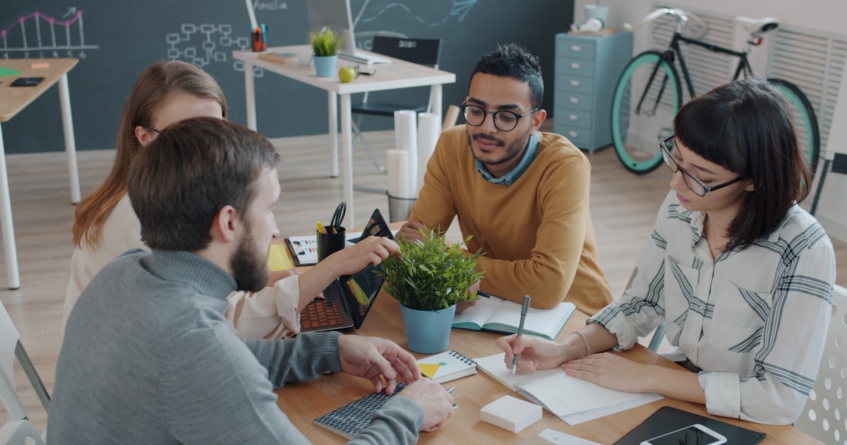 Equipe comercial reunida ao redor da mesa discutindo as metas e o plano da campanha de incentivo de vendas da pequena empresa.