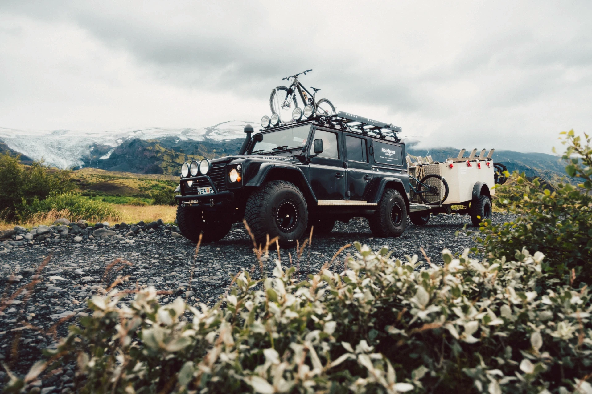 big tyre landrover defender with bike on top and biketrailer
