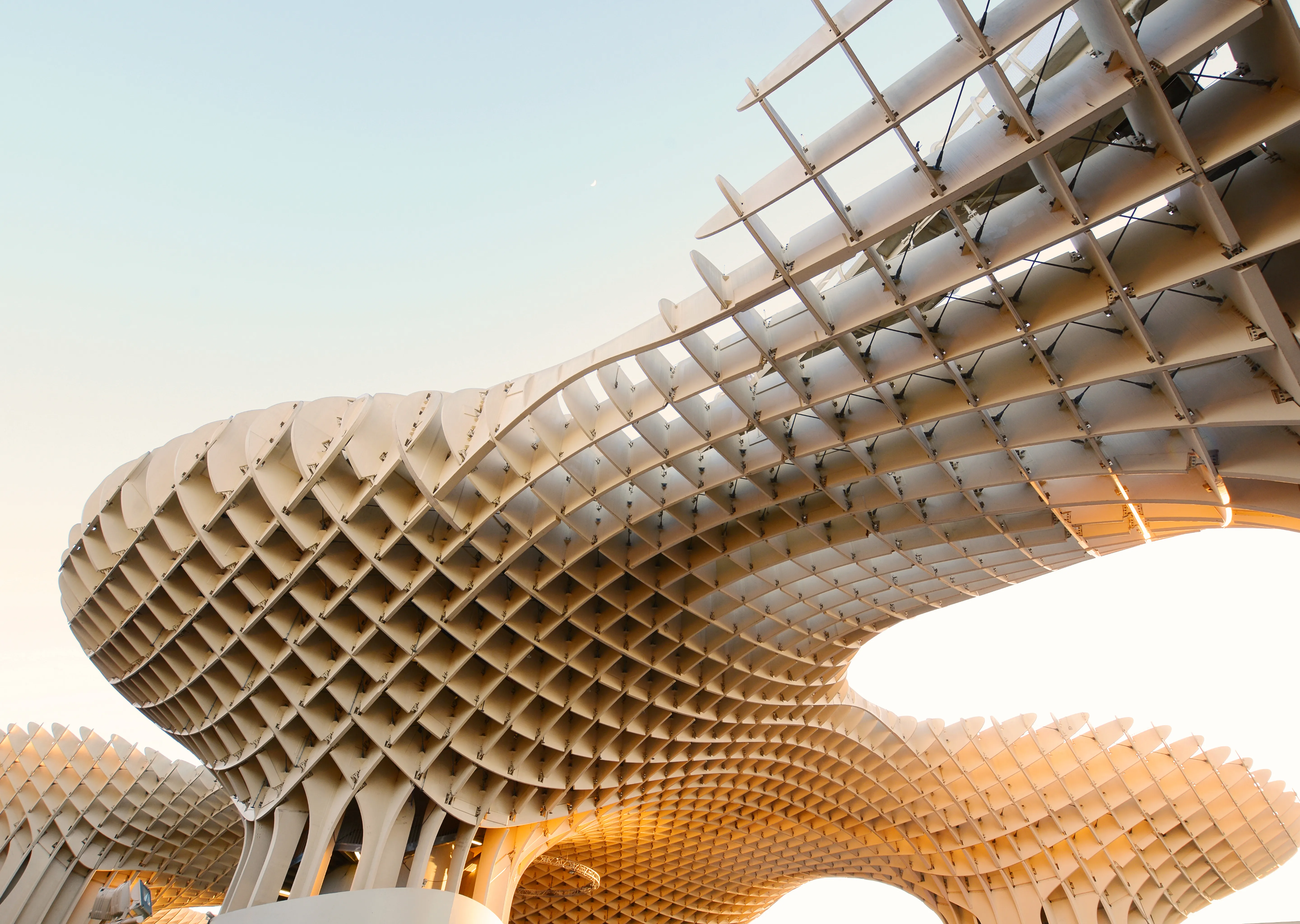 Modern undulating wooden lattice structure of the Metropol Parasol in Seville under a clear sunset sky.