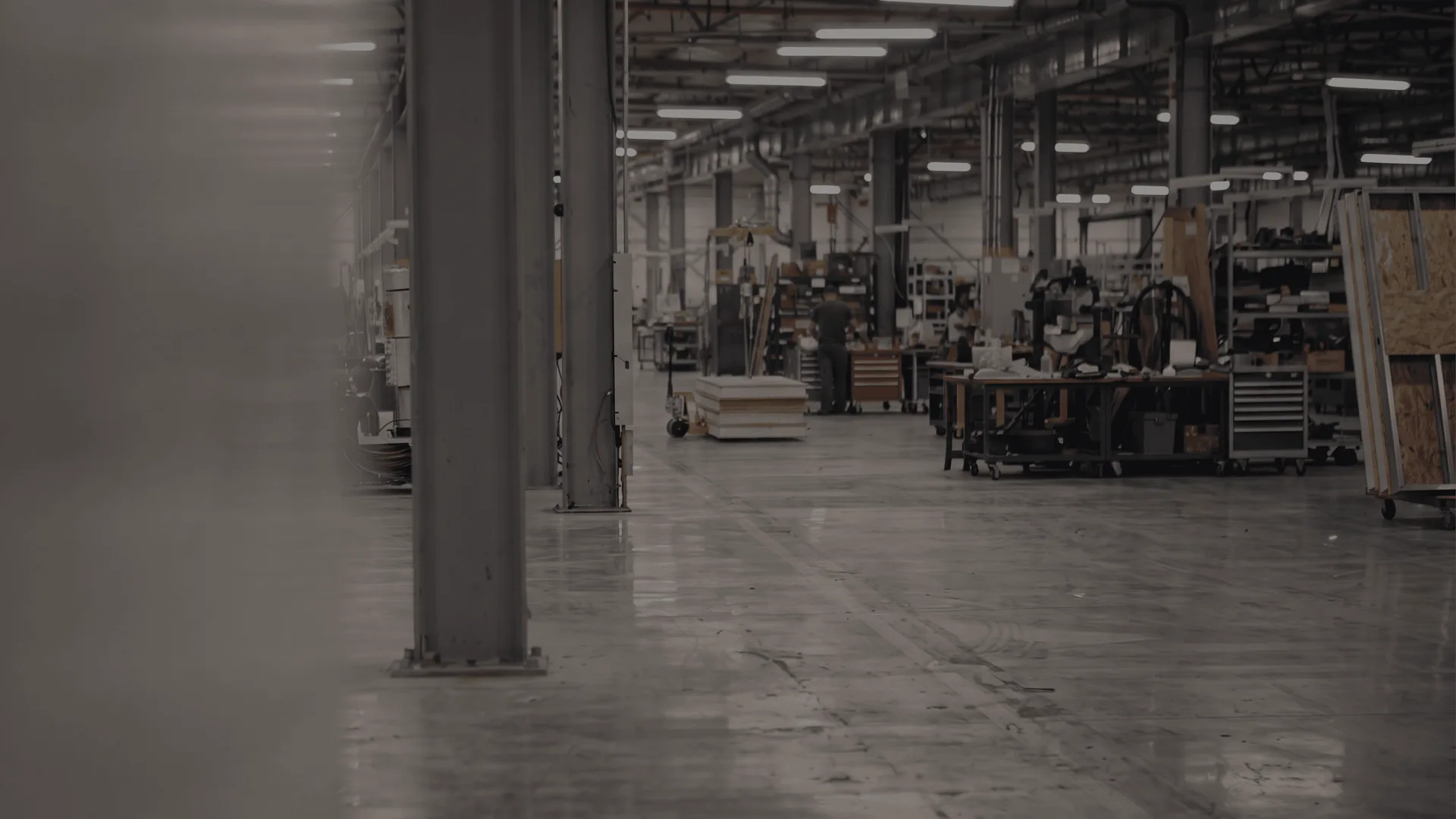 Interior of the empty Therm-O-Disc plant: a long concrete factory floor with structural columns, overhead lighting and idle workbenches