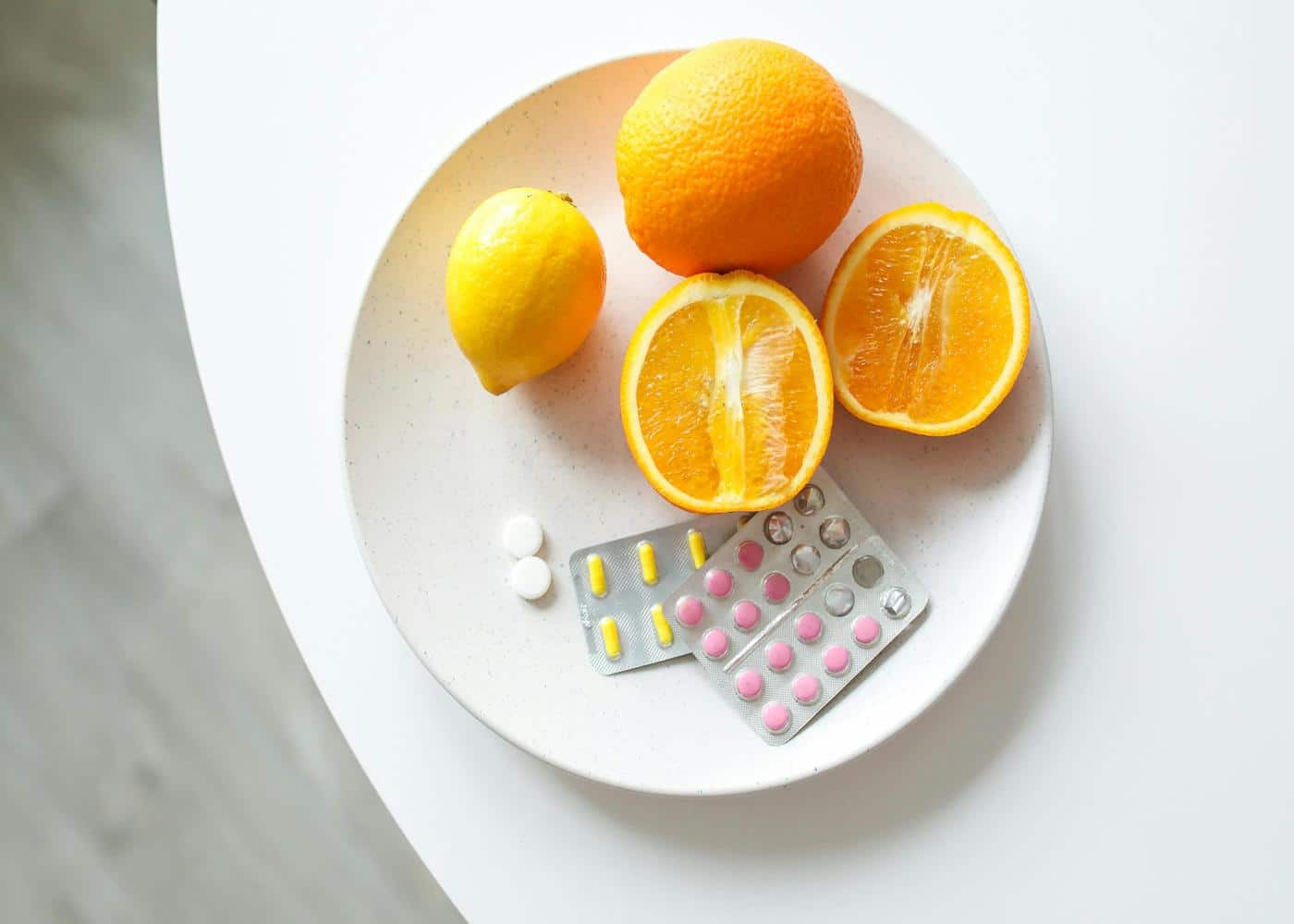 Oranges and immune system supplements on a white plate