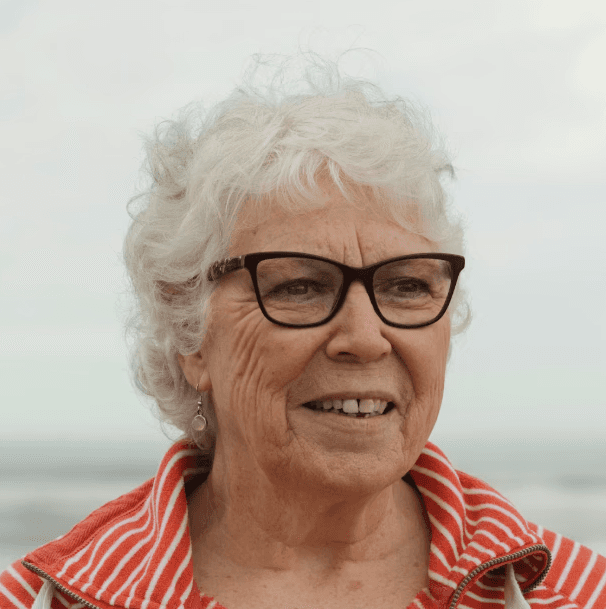 a young man wearing glasses standing in front of a mountain