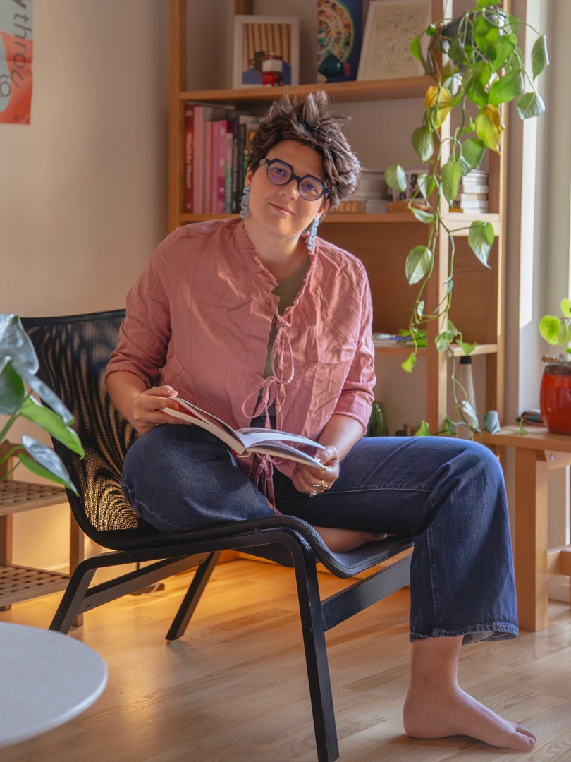 A thoughtful young person with dark hair gazes to the side, captured in soft black and white lighting.