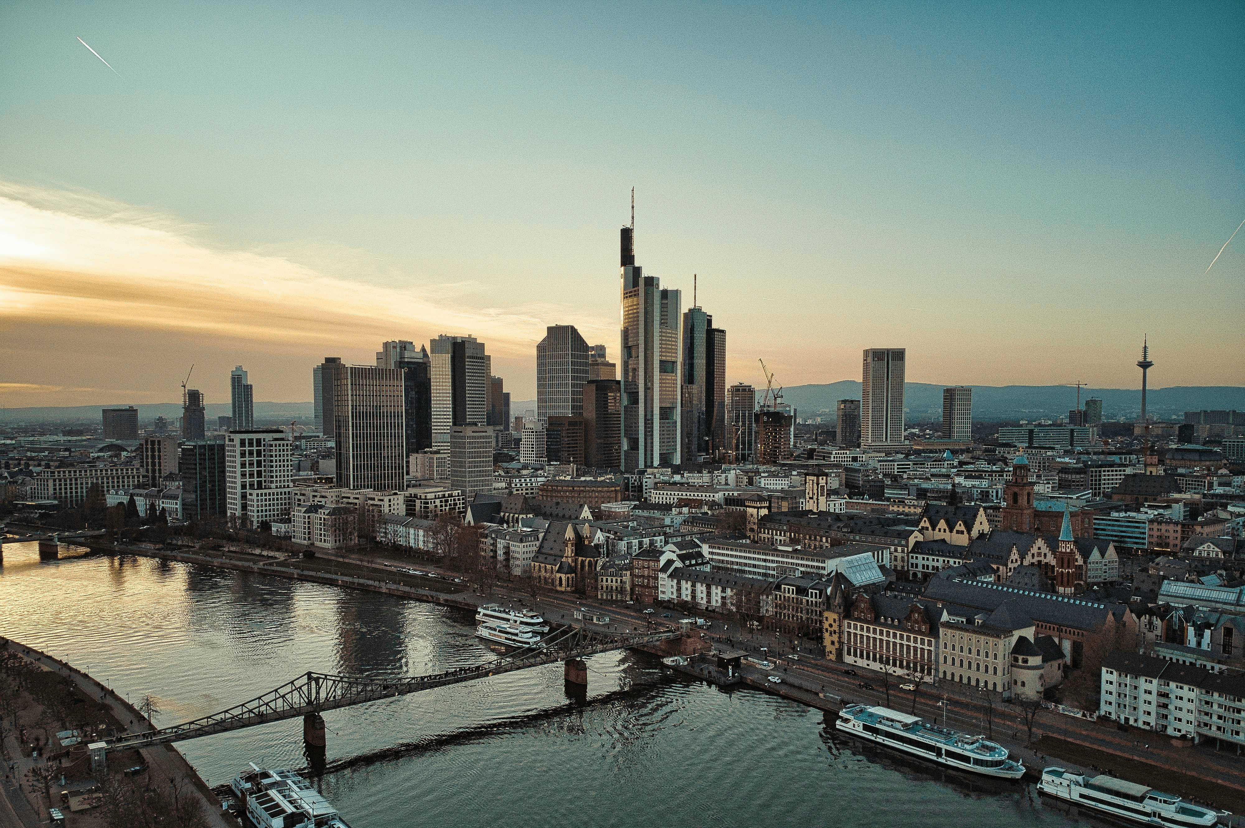 Frankfurt Skyline bei Sonnenuntergang mit Blick auf den Main, Brücken und Hochhäuser, Deutschland. 