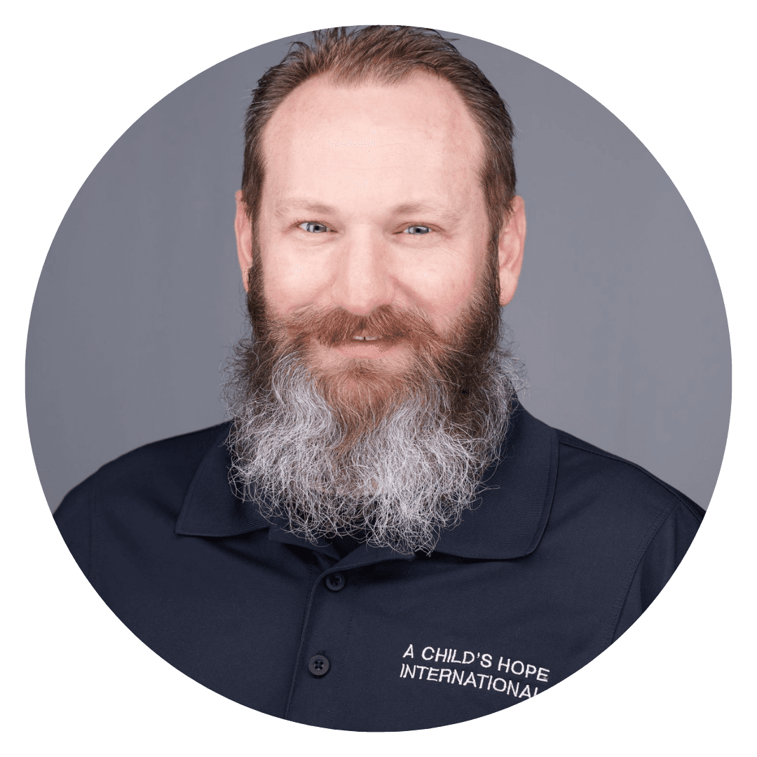 Headshot of Eric Whitmer, smiling with a long gray beard and short hair. He is the Director of Humanitarian Relief.
