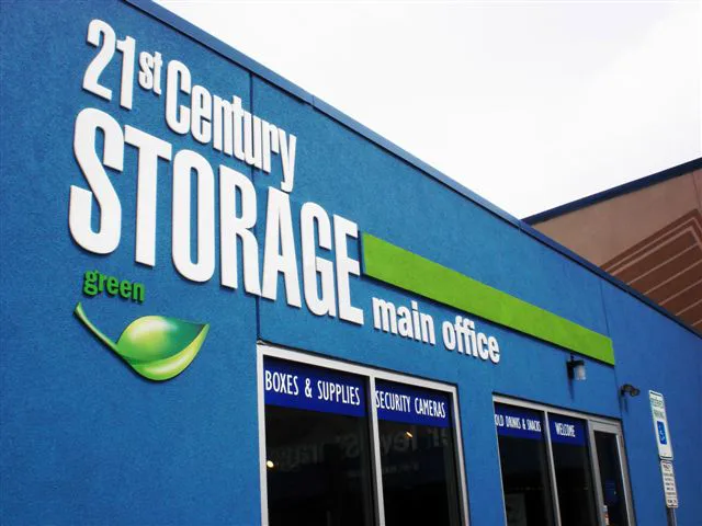 Bright blue building with bold white "21st Century STORAGE" sign, a green leaf icon, and "main office" text. The building appears modern and clean.