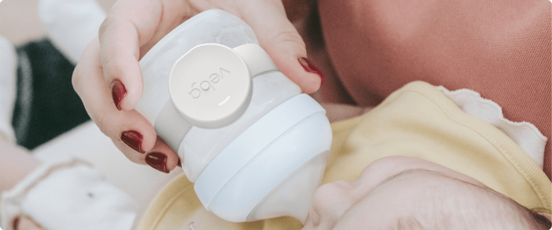 Woman feeding a baby with a smart baby bottle monitor attached to the bottle, tracking feeding data in real-time while ensuring accurate monitoring.