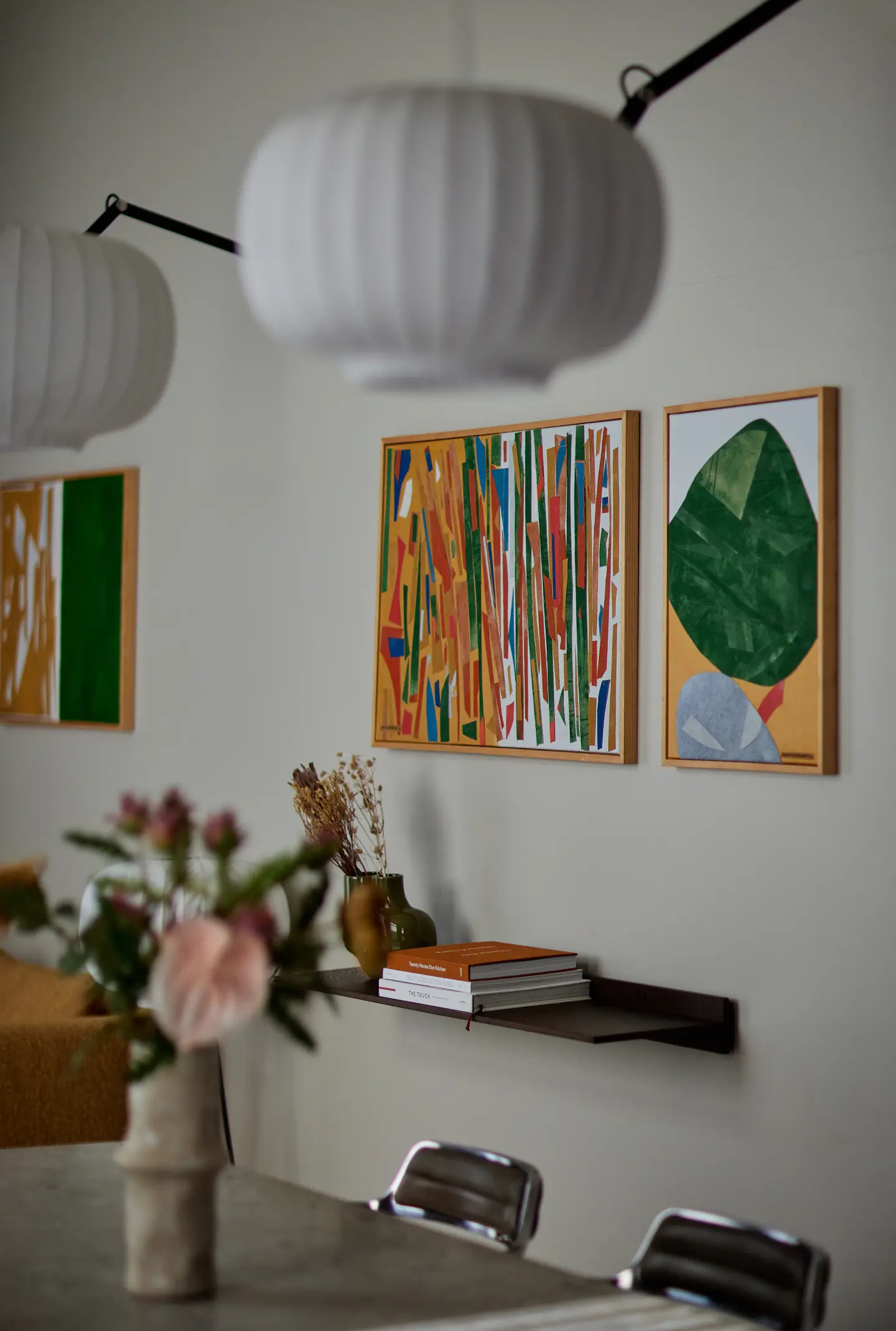 Close view of colorful framed artwork, pendant lights, and a flower arrangement above the meeting table