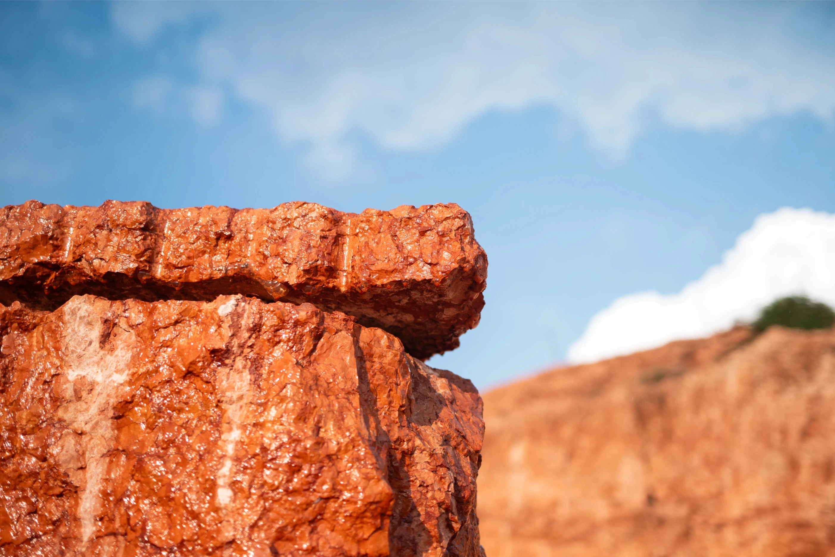 Dettaglio ravvicinato di una roccia rossa lucida in cava, materia prima per progetti artistici iStone Arte, valorizzazione del brand attraverso l’arte naturale