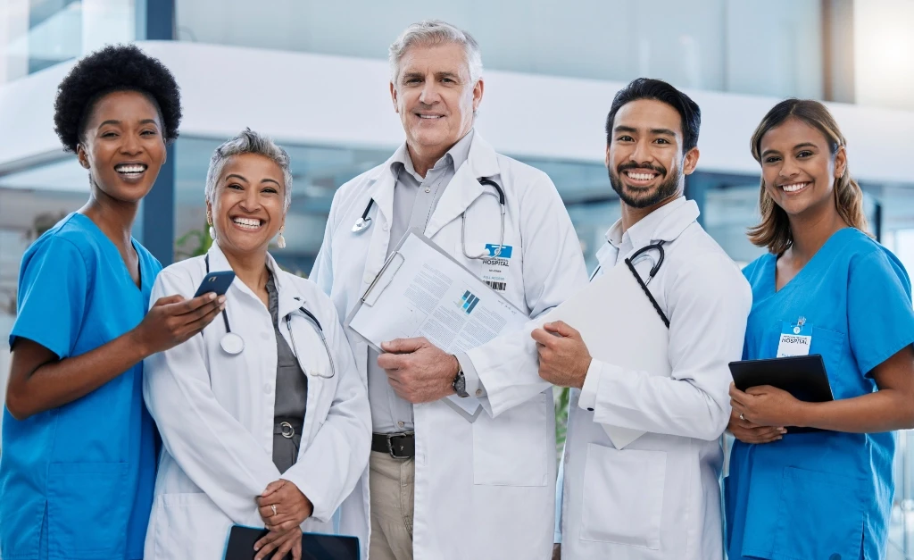 Mixed of group of doctors, standing and smiling at the camera.