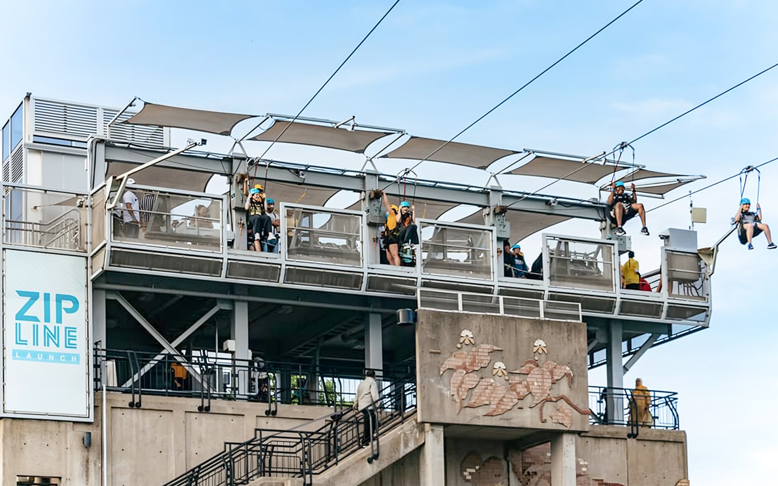 Zipline launch platform with people ziplining towards the falls.