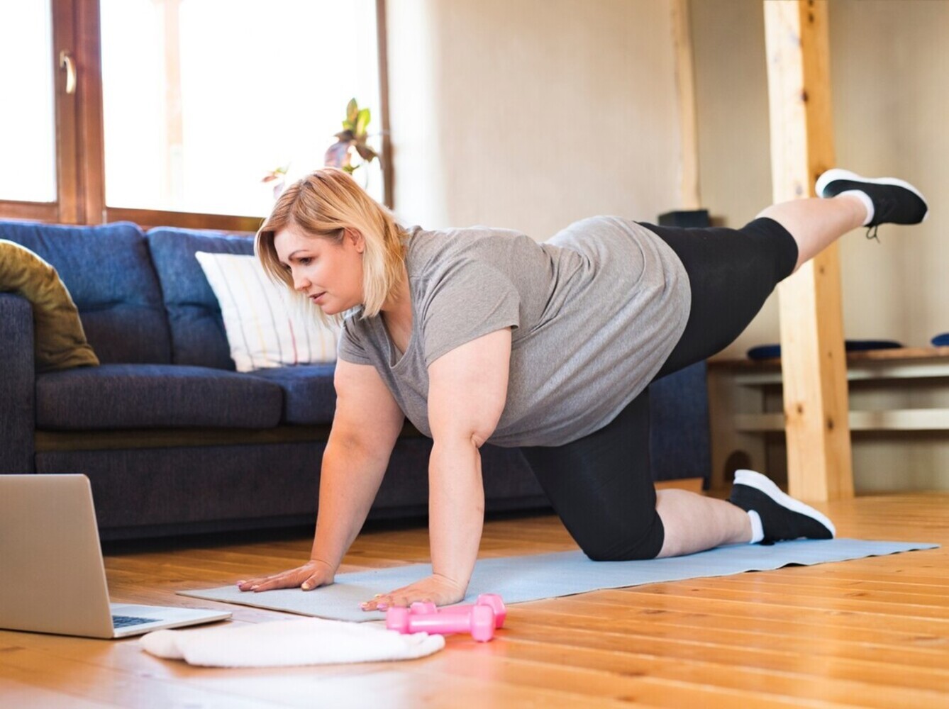 overweight woman doing gentle exercise for weight loss at home while following an online class