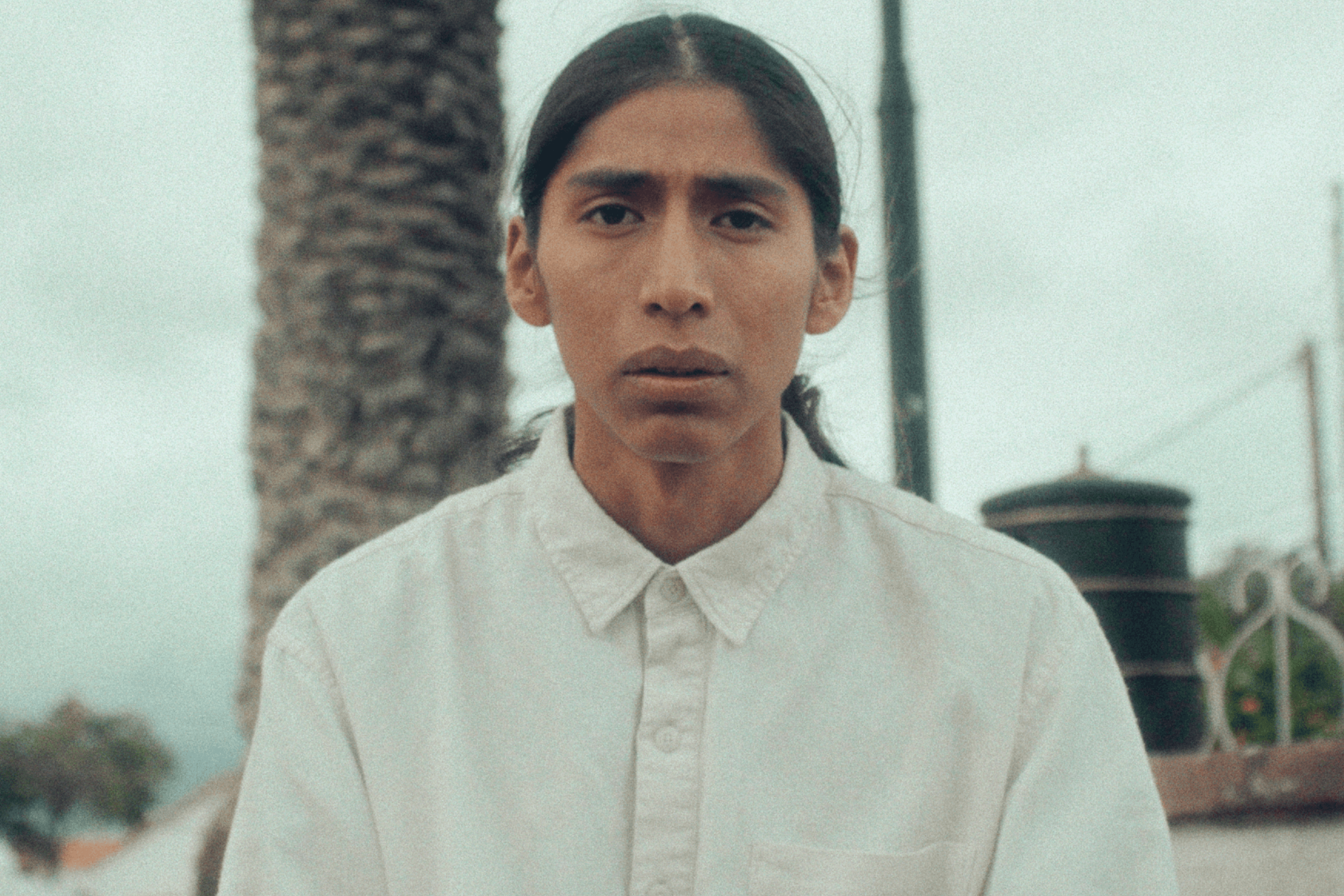 Woman in a light suit sitting thoughtfully against a terracotta wall