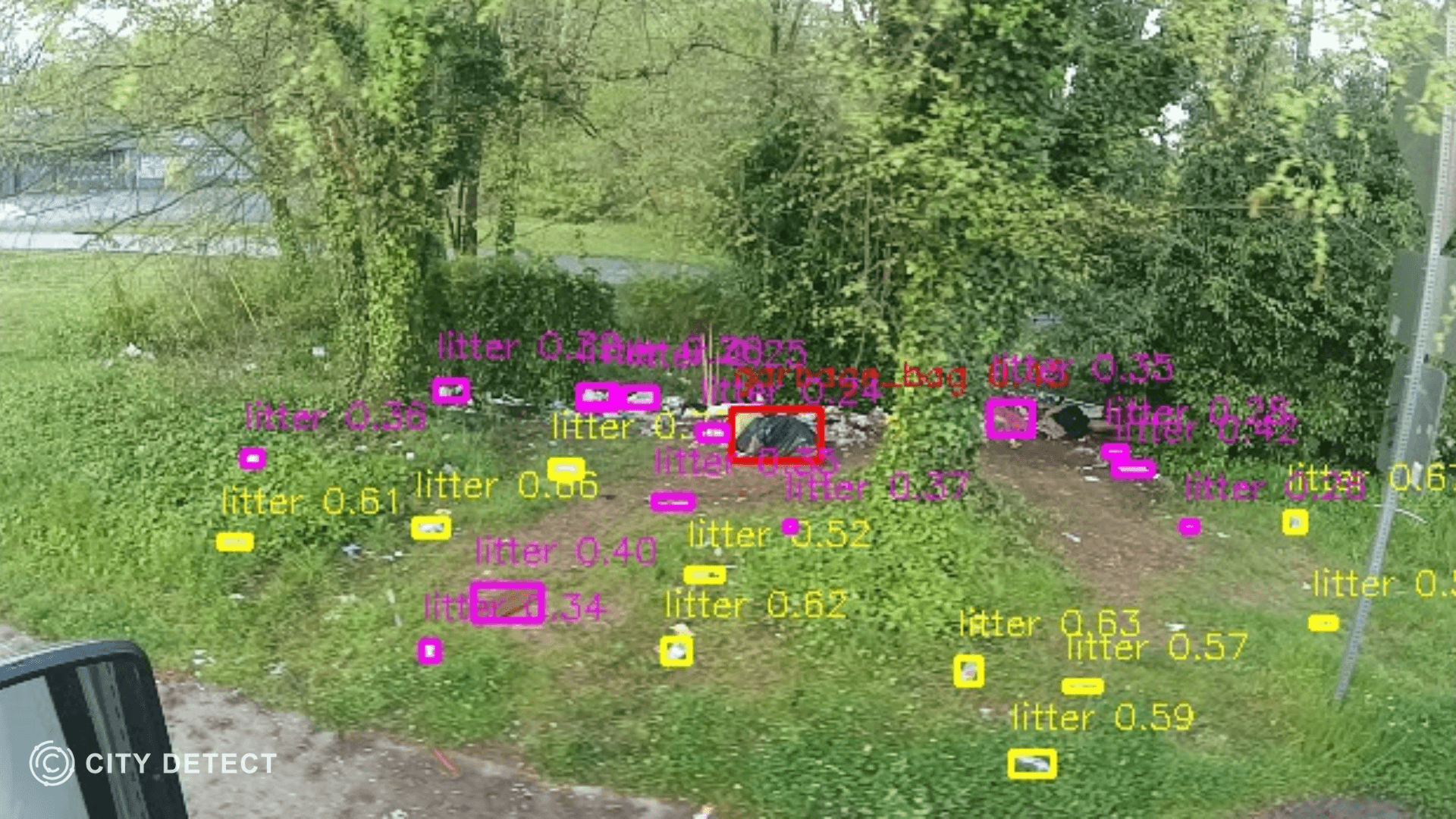 A City Detect camera detects litter and a small object on a patch of grass near bushes.
