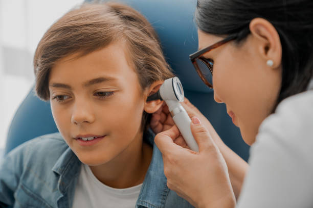 A child receives an ear exam from a healthcare professional using an otoscope. They are focused and calm.