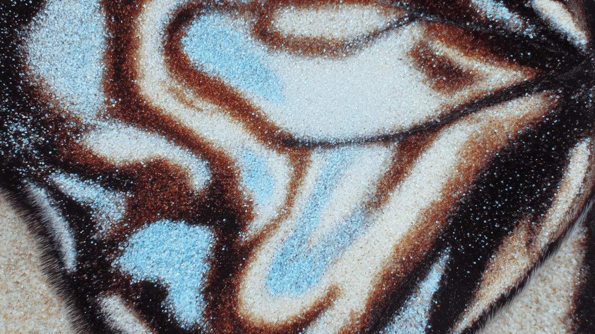 Close-up of a textured surface with intricate patterns in brown, white, and blue, resembling natural formations with a sparkling effect.