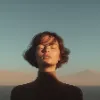 Minimalist portrait of a woman with short hair and eyes closed in golden hour sunlight.