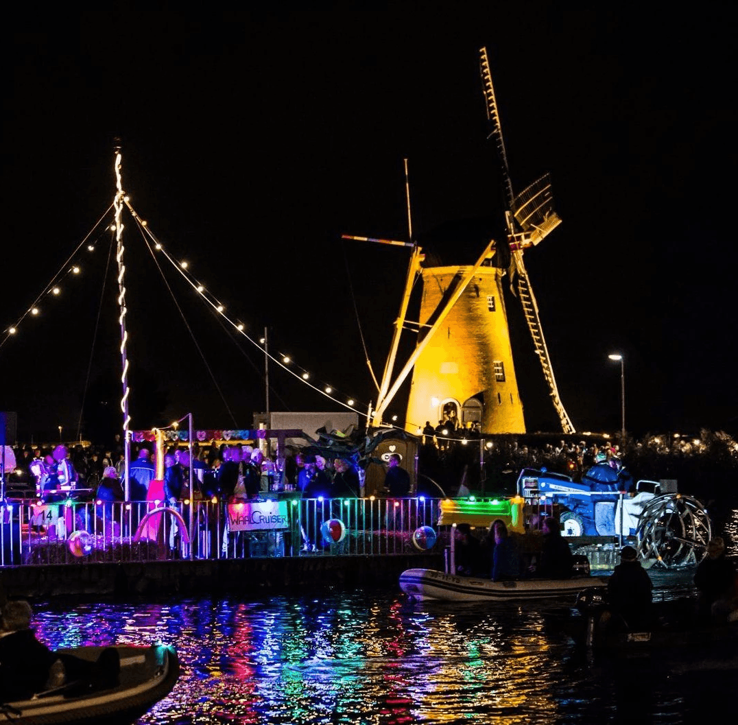 Rear view of a man jogging down a paved city sidewalk next to a building covered in graffiti.