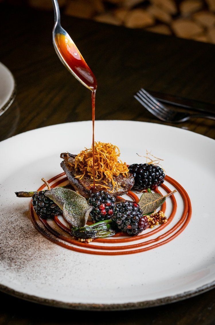 Close-up of sauce poured onto a fine dining plate, reflecting the precise technique and finishing artistry practiced in the Dhoom kitchen.
