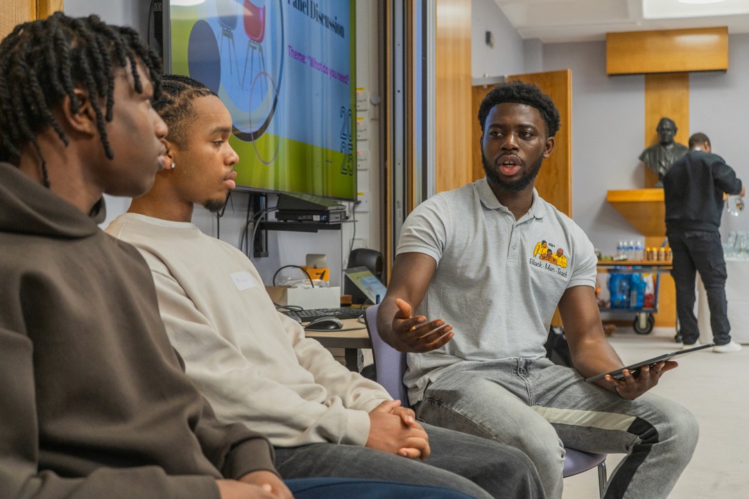 A teacher asks two young people a question at a panel event