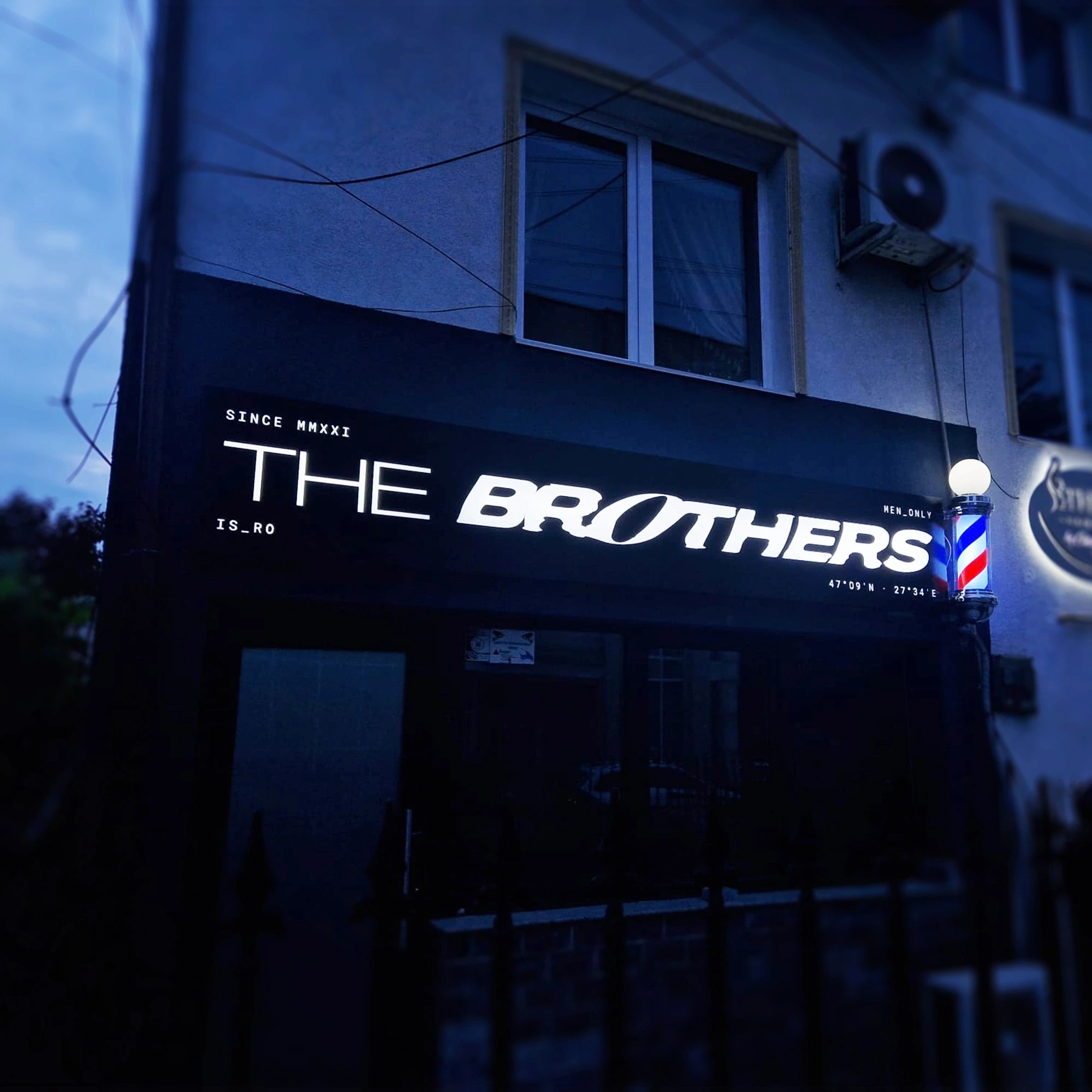 Reclamă luminoasă The Brothers pe fațadă, iluminată seara