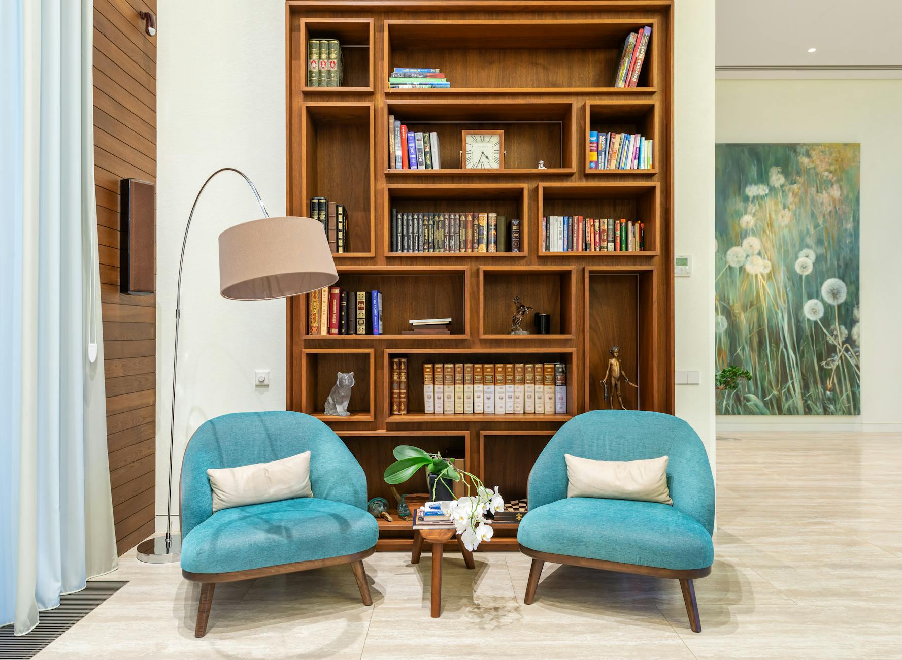 A cozy reading nook featuring floor-to-ceiling wooden bookshelves and a person comfortably reading a book in a chair.