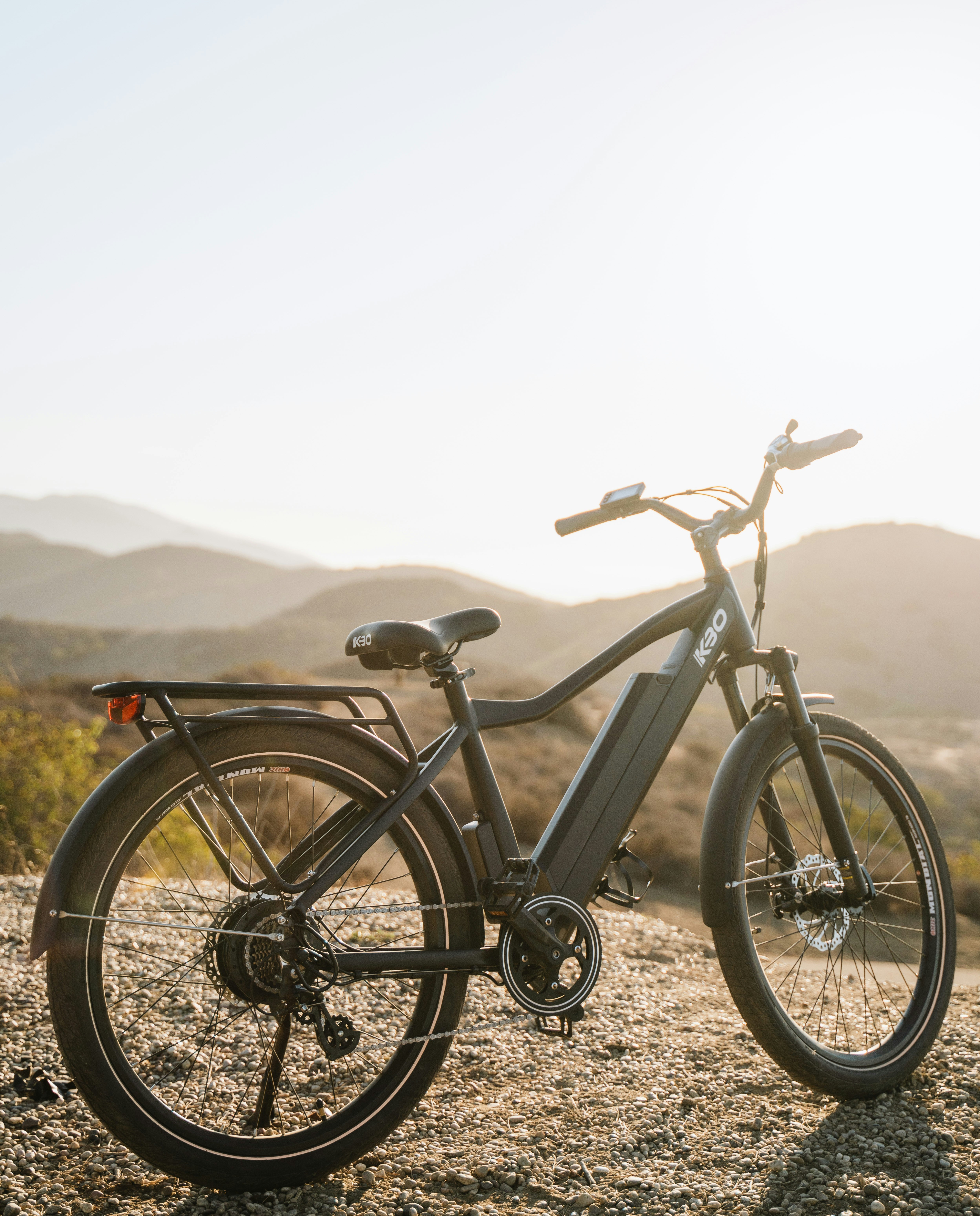 Vélo de ville à assistance électrique (VAE) noir, équipé pour le milieu urbain, stationné au coucher du soleil.