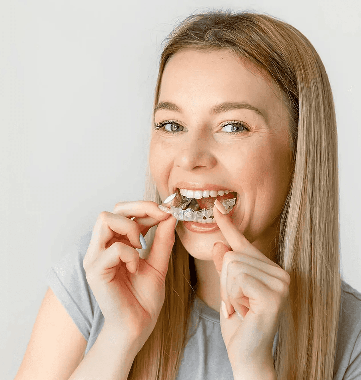 A woman smiles and holds invisalign clear aligners with a case, showcasing a certified invisalign provider at Bella Medical Centre