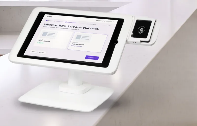 The Gravity Greeter check-in tablet on a lobby counter, asking the patient to scan their driver’s license and insurance card