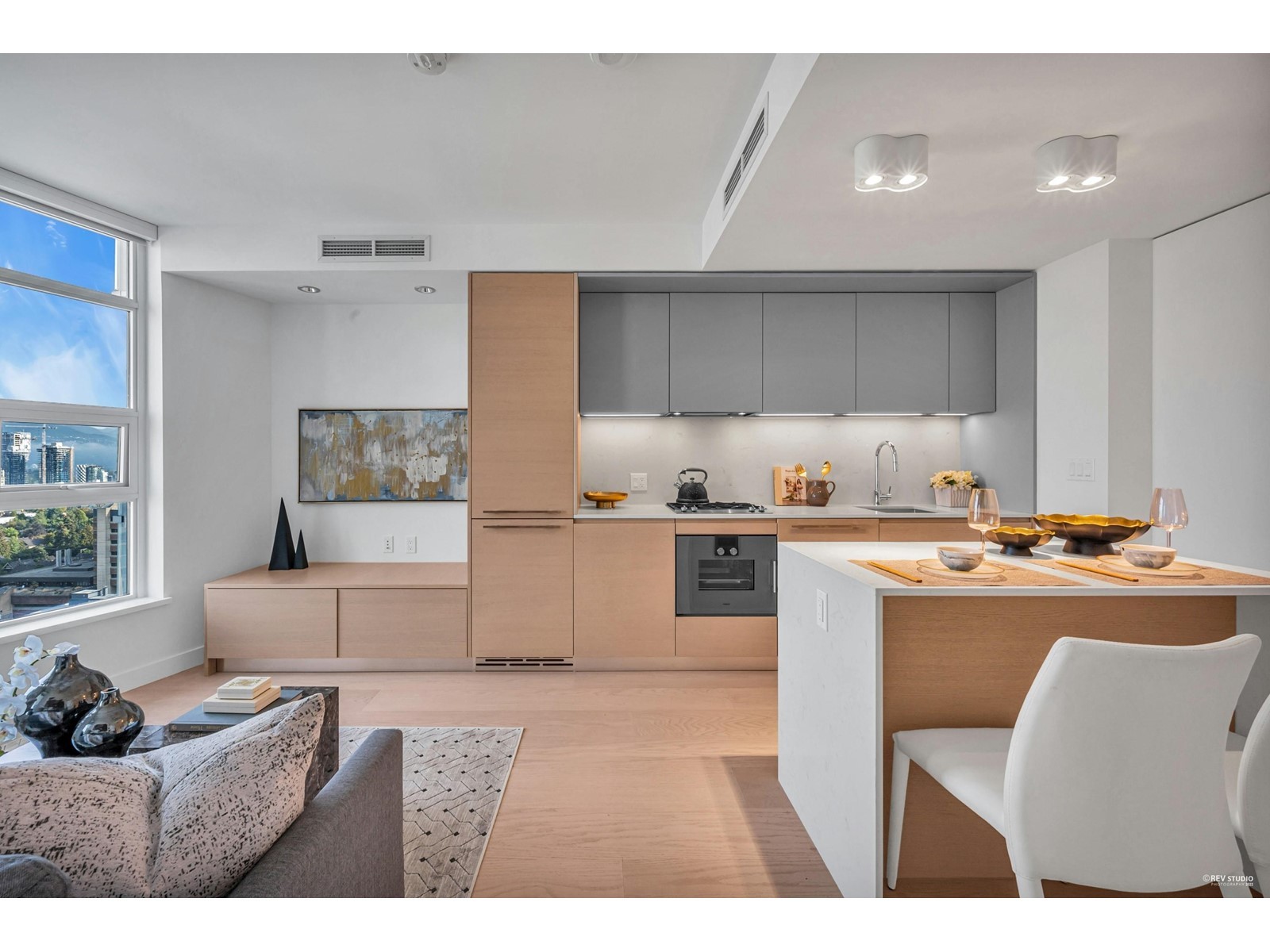 Modern kitchen with light wood cabinetry, white appliances, and a cozy seating area featuring a sofa and dining table.