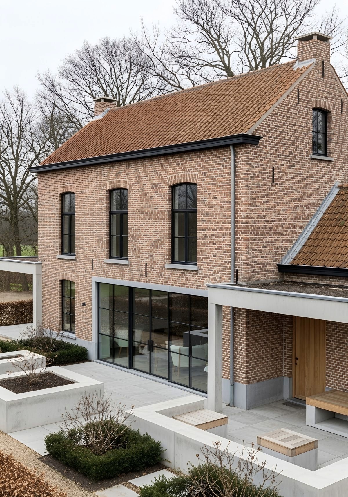 A modern house with large windows and a flat roof, surrounded by greenery against a clear blue sky.