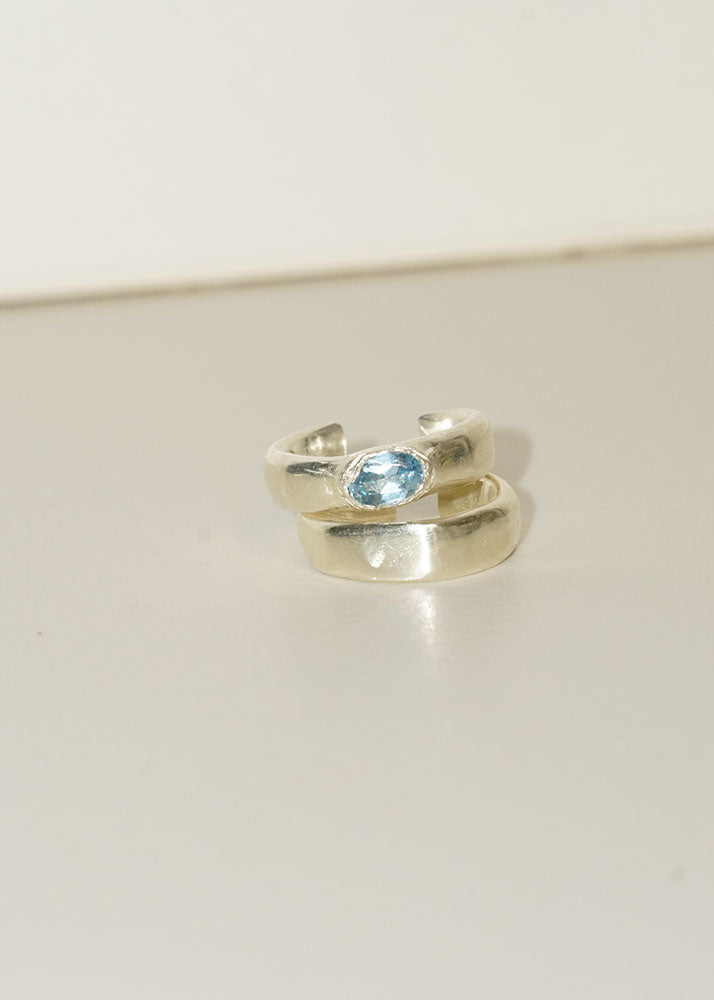 Silver ring with a blue gemstone on a light gray background