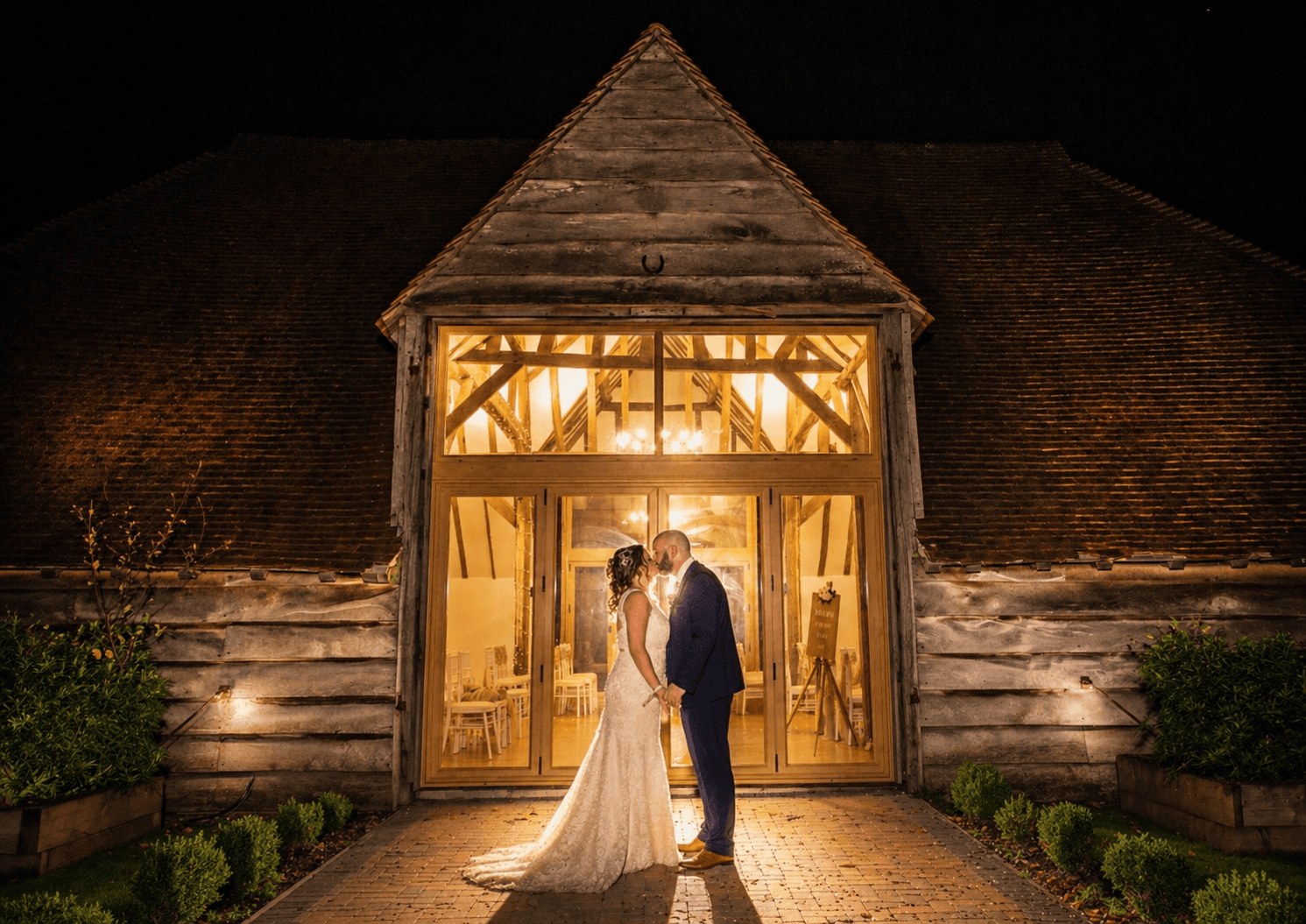 Wedding portrait: Bride in lace gown, veil, and tiara, holding bouquet. Groom in black tuxedo.