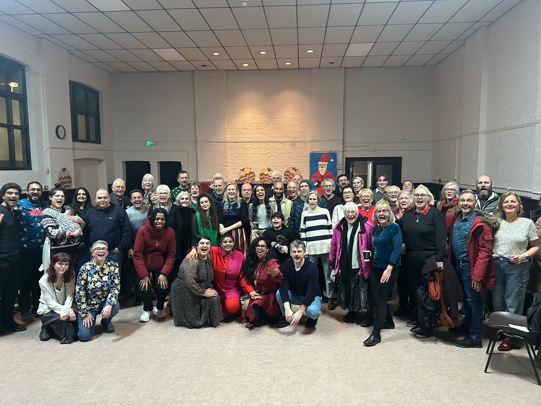 Diverse group of people at a Community Hall at Christmas, posing for a photo.