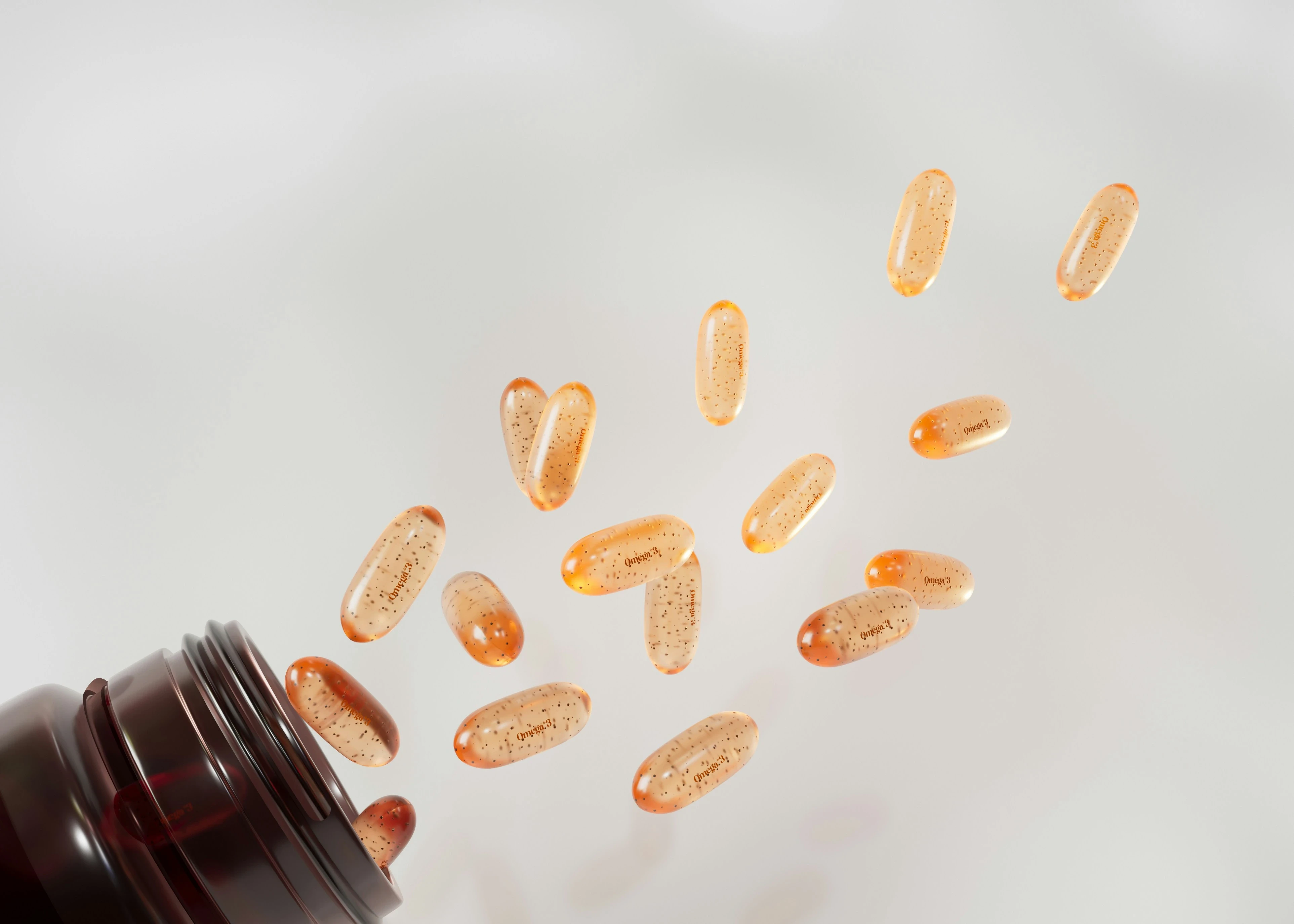 orange supplement pills fall out of a black pill bottle onto a white surface