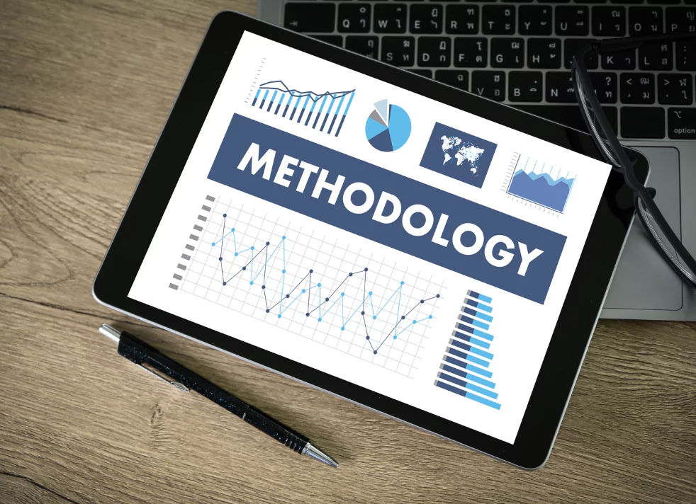 tablet that shows the word methodology with line graphs, pie charts, a map of the world, sitting on top of a computer