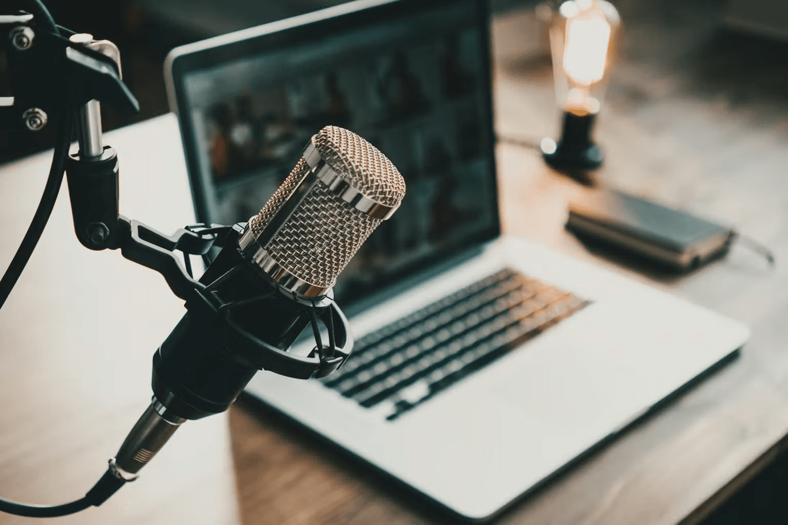 A studio microphone beside an open laptop - Podcast Clips for Social Media