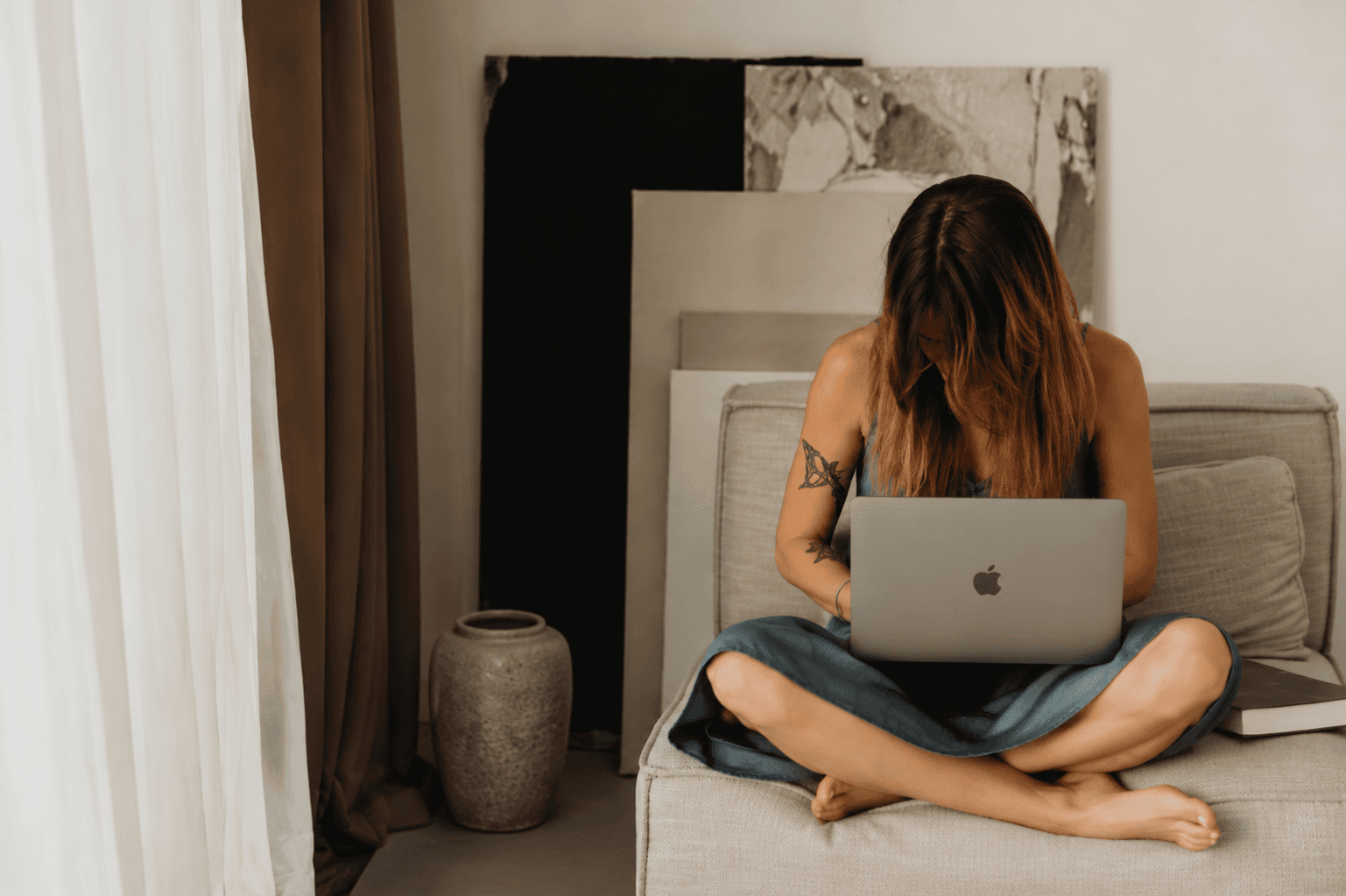 Woman sitting in a chair indoors holding a mug and looking to the side.