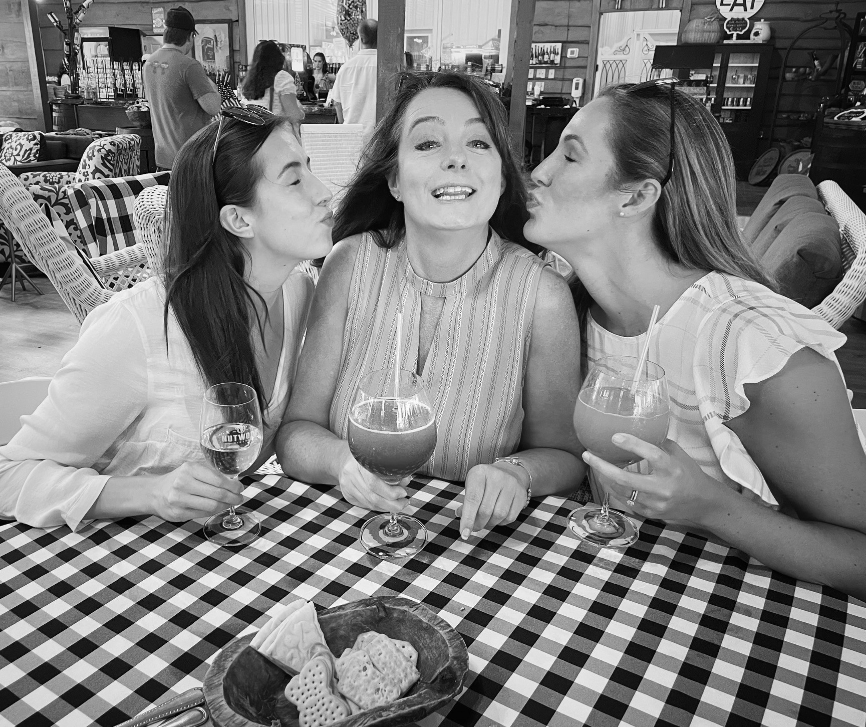 Three women each holding a glass of wine pose for a picture