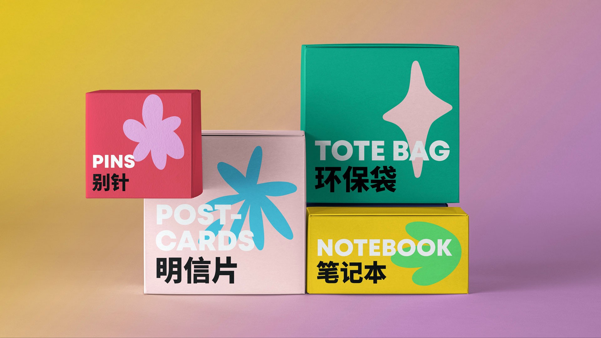 Four boxes are stacked on a gradient yellow-to-purple background. From left to right, the boxes are labeled “PINS” in red with a pink flower, “POST-CARDS” in white with a blue flower, “TOTE BAG” in green with a white star, and “NOTEBOOK” in yellow with a green leaf. The boxes are labeled with Chinese characters.