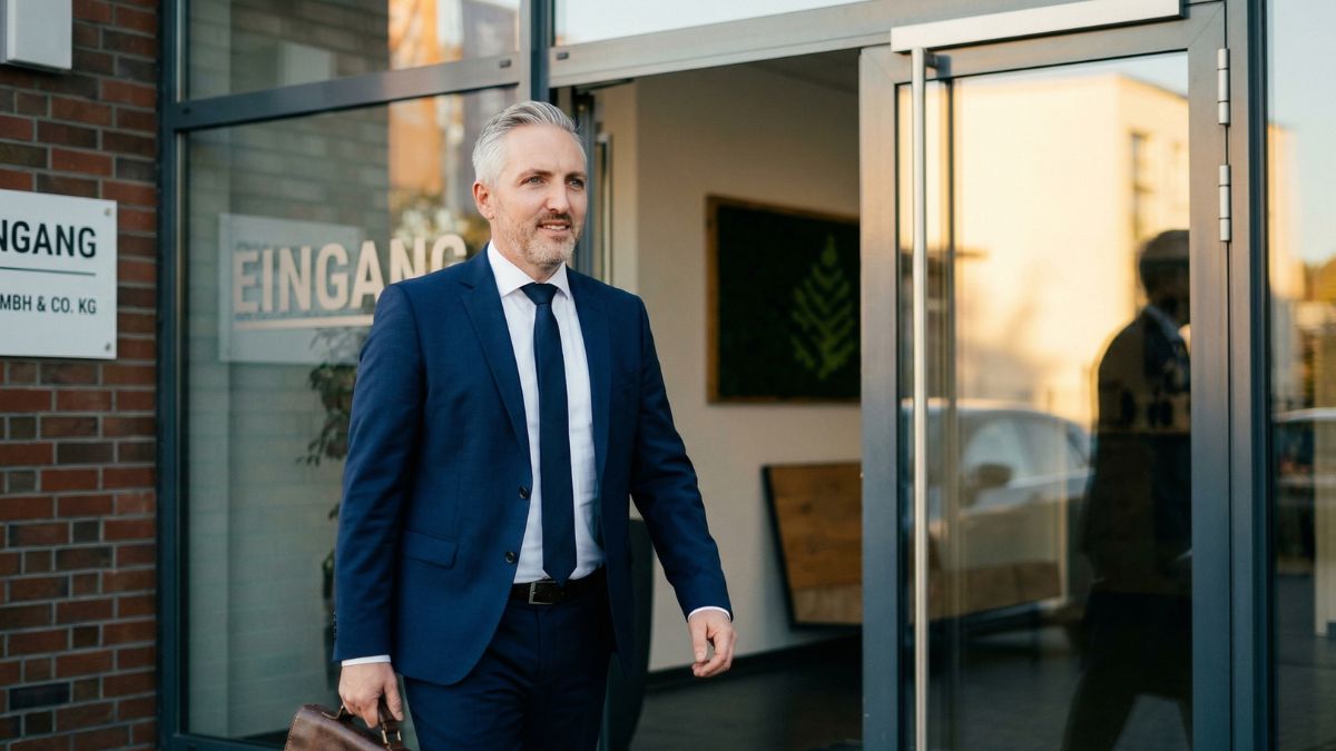 Person mit Aktentasche betritt den Eingang eines mittelständischen Unternehmens zur BG-Prüfung