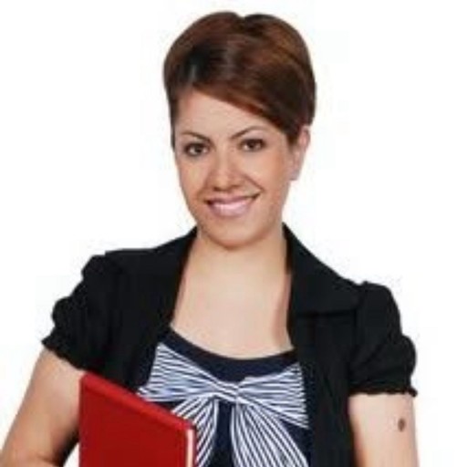 A young woman with long brown hair smiles warmly against a green background, dressed in a black jacket and white shirt.