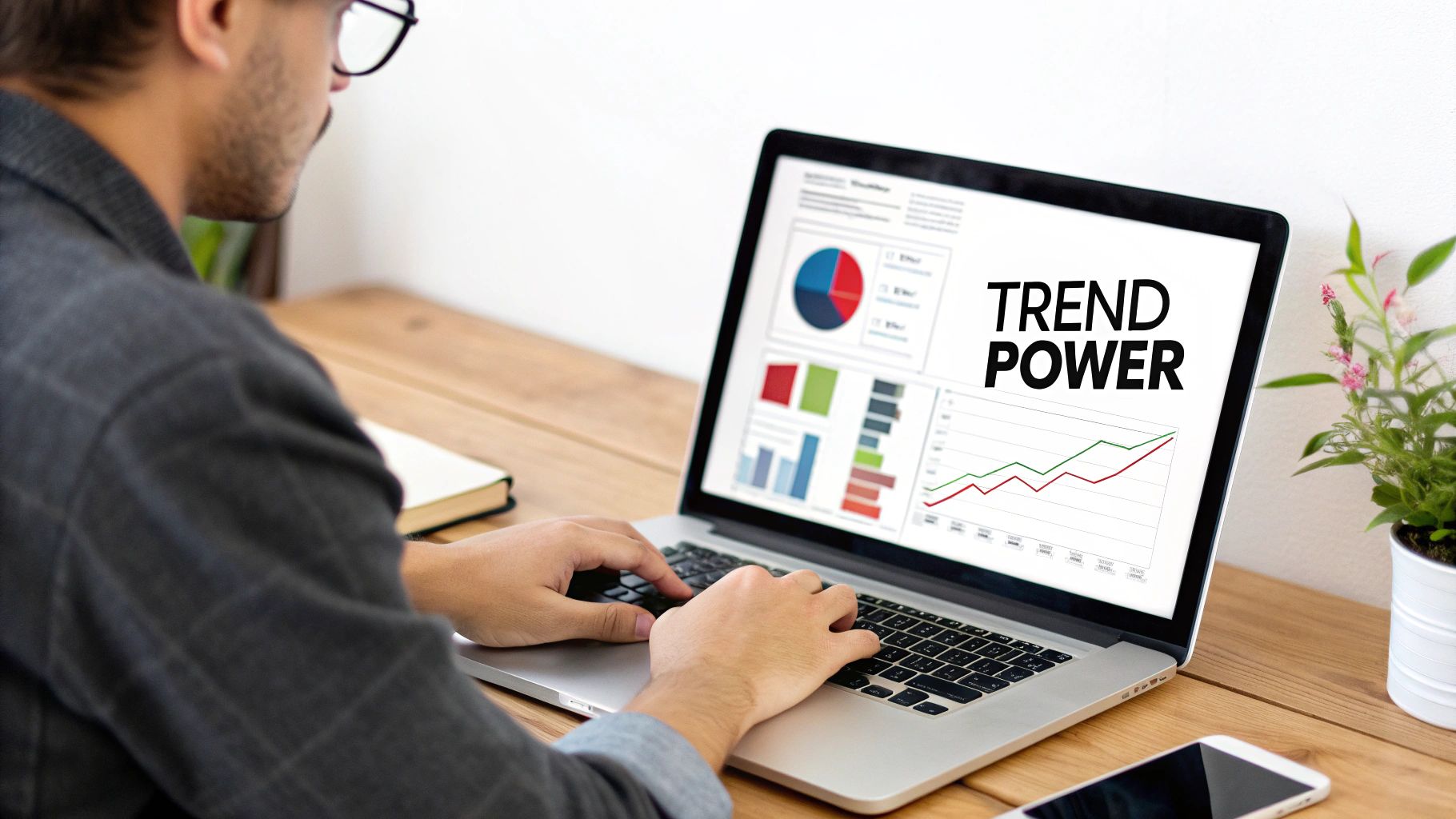 Man typing on a laptop displaying 'Trend Power' text and business data charts.