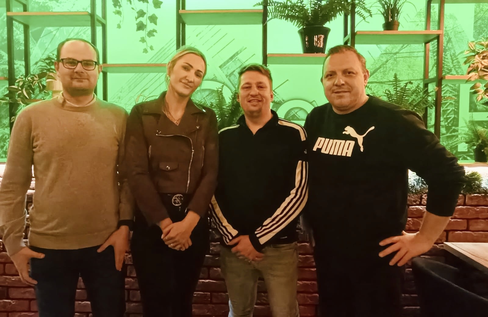 A woman with red hair in a lavender coat and scarf poses against a neutral background, showcasing a stylish and elegant look.